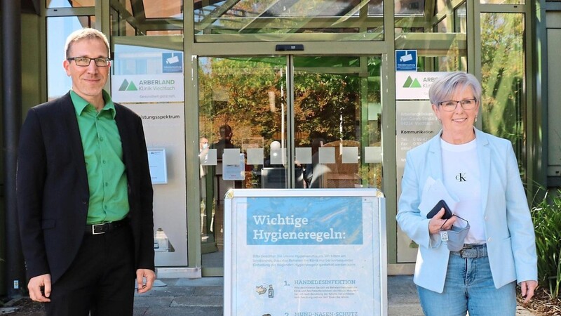 Kliniken-Vorstand Christian Schmitz und Landrätin Rita Röhrl stehen vor der Arberlandklinik Viechtach neben einem Schild, das Krankenhausbesucher auf die Hygieneregeln hinweist.