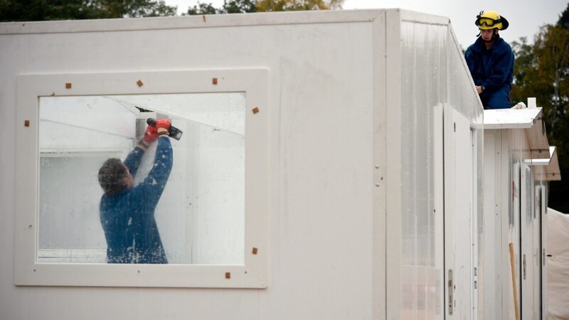 Mitarbeiter des technischen Hilfswerks (THW) bauen am 22.10.2015 in der Flüchtlingsnotunterkunft Scheuen bei Celle (Niedersachsen) die neuen Schnellbauhütten auf.
