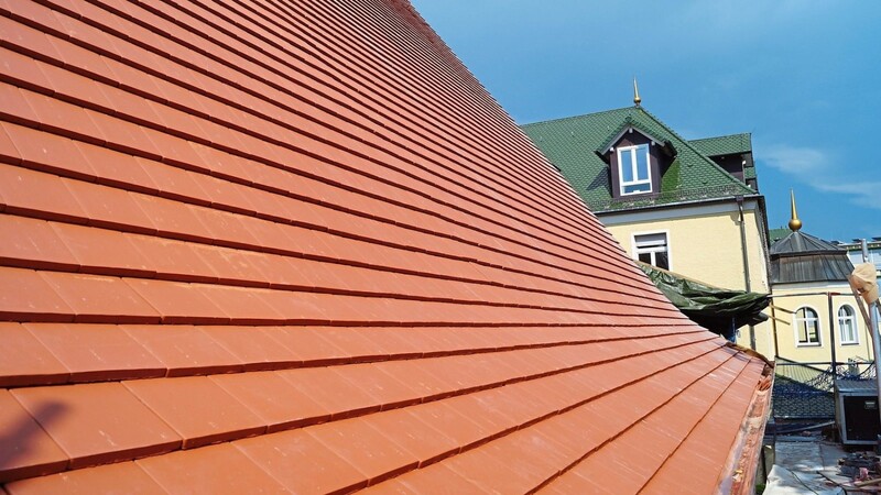 Neu mit roten Kirchenbibern ist das Langhaus-Dach eingedeckt, im schönen Kontrast zum grünen Dach des IsarParks.