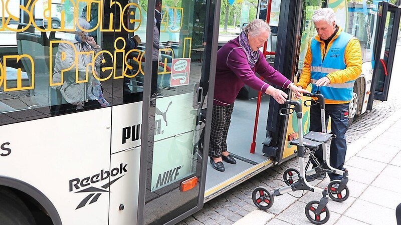 Busbegleiter Peter Gruber hilft einer Seniorin mit Rollator beim Aussteigen aus dem Stadtbus.