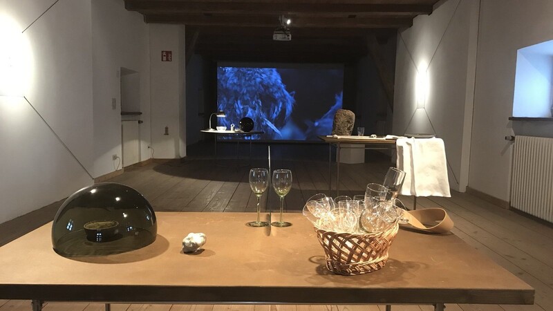 Im Vordergrund Burkard Blümleins "Tischgespräch" mit Möbiusband (rechts hinten), ganz hinten an der Wand Chris Bierls Video-Schleife "Die Versammlung der Vögel"