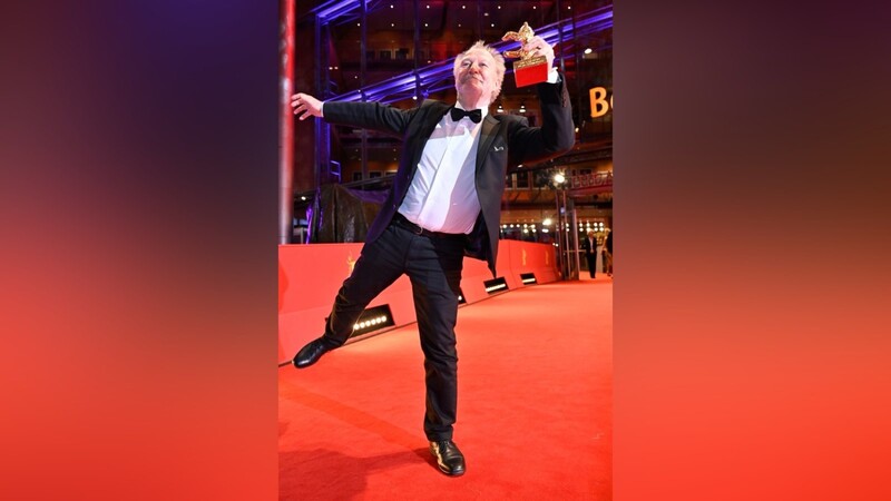 Nicolas Philibert tanzt mit seinem Goldenen Bären auf dem Roten Teppich der Berlinale