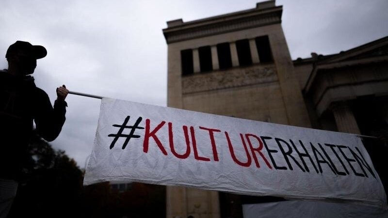 Zwei Männer halten auf dem Königsplatz in München ein Banner mit der Aufschrift "#KulturErhalten".