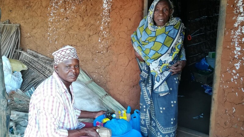 Rama, ein Vereinshelfer vor Ort übergibt einer armen alten Frau Lebensmittel und Hygieneartikel, gespendet von der Ukunda-Hilfe.