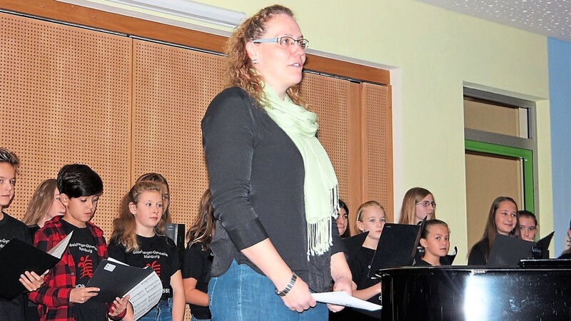 Angelika Hagl und im Hintergrund die Chorklasse des Gabelsberger-Gymnasiums bei den Darbietungen zu "Jugend gestaltet Freizeit" in der Mainburger Grundschule.