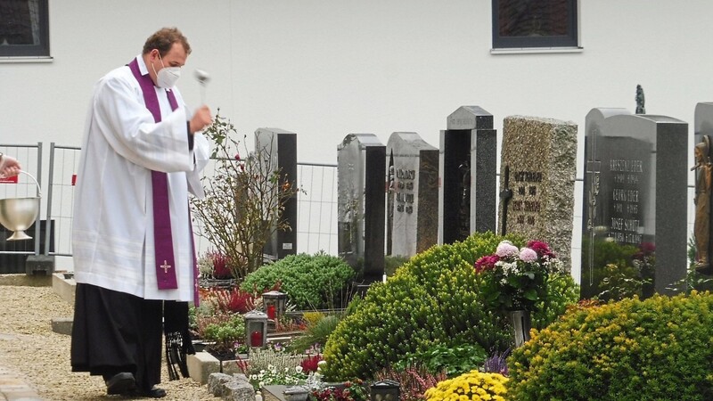 Jedes einzelne Grab besprengt Kaplan Matthias Zellner auf dem Friedhof mit Weihwasser.