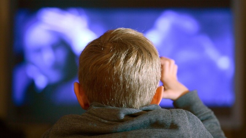 Ein Junge sitzt vor dem Fernseher.