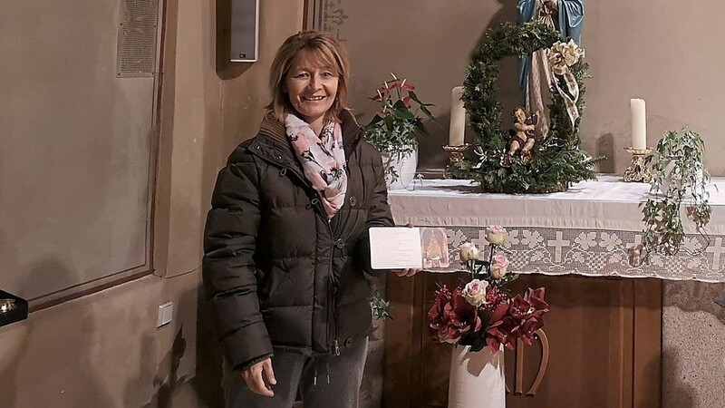 Alexandra Linzmeier überreicht die Weihnachtspostkarten an Pfarrer Godehardt Wallner.