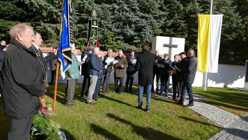 Bürgermeister Christian Dobmeier bei seiner Ansprache am Kriegerdenkmal im Freien mit Pater Raphael und den Fahnen.