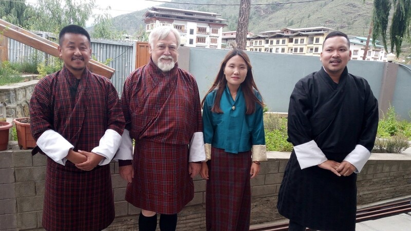 Traditionelle Kleidung ist in Bhutan für Männer der Gho, wozu lange Strümpfe getragen werden. Es handelt sich um ein mantelartiges Kleidungsstück, das bis zum Boden reicht, aber mit einem speziellen Gürtel aus Yak-Wolle hochgezogen nur bis zu den Knien geht. Im oberen Teil entsteht so viel Platz, um alles Mögliche zu verstauen. Johann Reif (2.v.l.) spricht von der "größten Geldbörse der Welt". Allerdings ist das Anziehen kompliziert und zeitintensiv.
