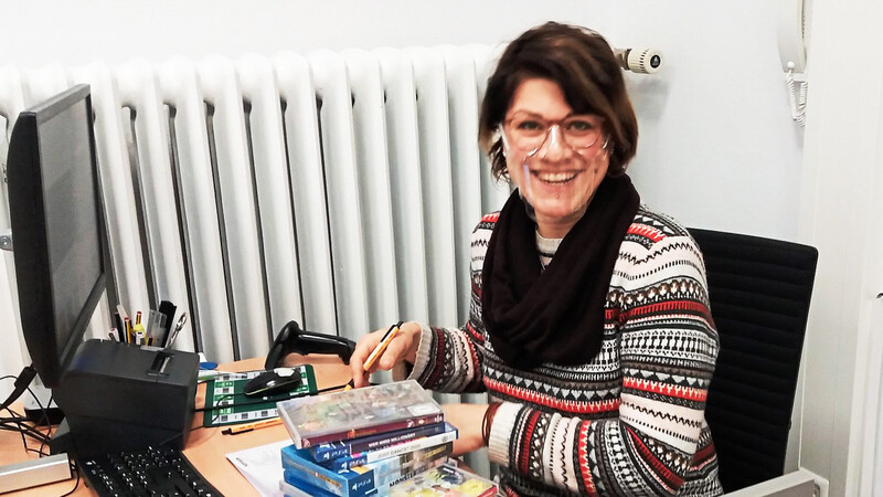 Büchereimitarbeiterin Simone Schmid mit Gesichtsschutz beim Auspacken neuer Bücher.