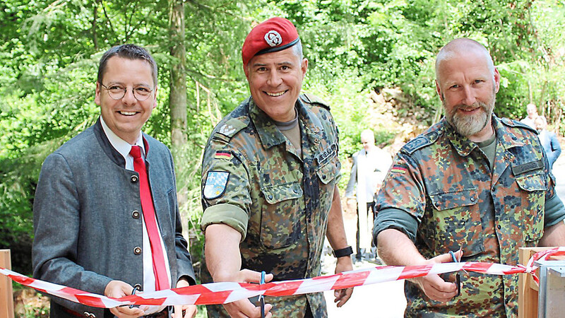 Bürgermeister Heinz Pollak, Oberstleutnant Ronny Schievelkamp und Stabsfeldwebel Spanner (von links) zerschneiden die Absperrung und geben die neue Brücke frei.