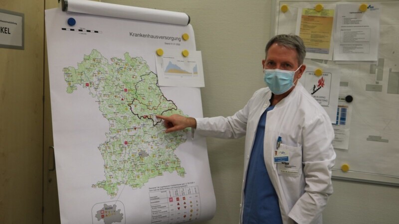 Dr. med. Markus Zimmermann zeigt auf einer Bayern-Landkarte seinen Zuständigkeitsbereich für die Koordinierung der Unterbringung von Covid 19-Patienten.
