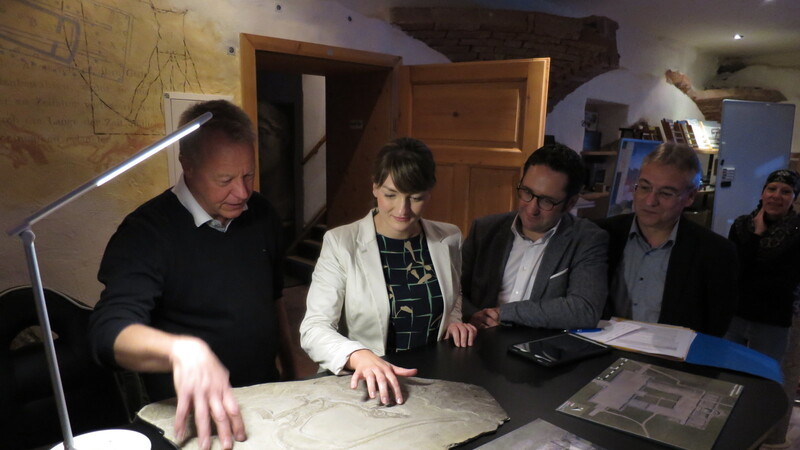 Martin Schaich zeigt Ministerin Judith Gerlach ein 3D-gedrucktes Duplikat eines versteinerten Sauriers. Ebenso staunen Landtagsabgeordneter Tobias Gotthardt und Bürgermeister Harald Hermann.
