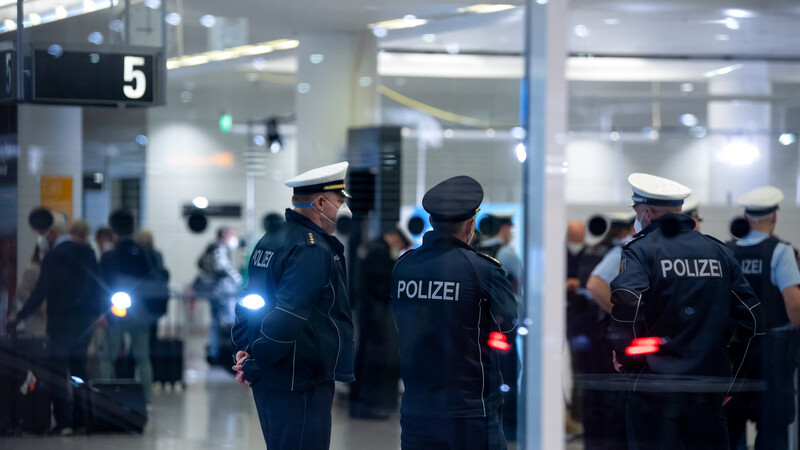 Polizisten stehen im Ankunftsbereich am Flughafen München und kontrollieren Passagiere, die zuvor mit einer Maschine der Lufthan