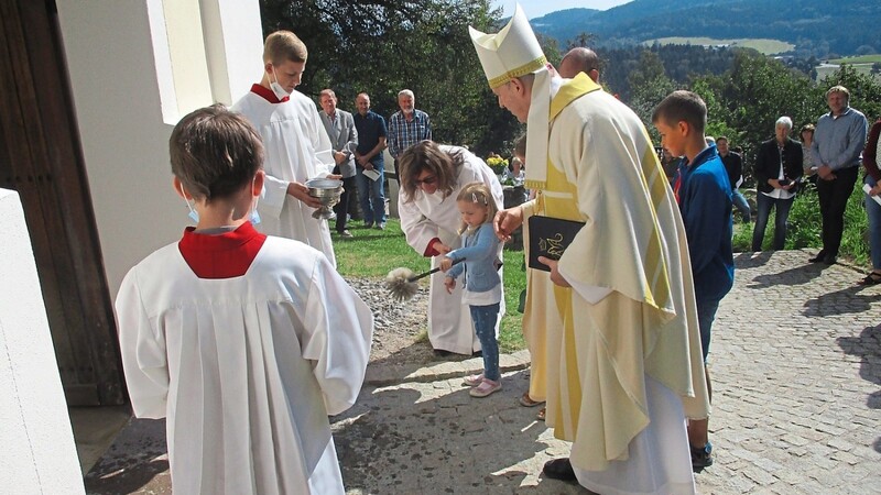 Weihbischof Reinhard Pappenberger hatte beim Weihwassersprengen eine kleine Helferin.
