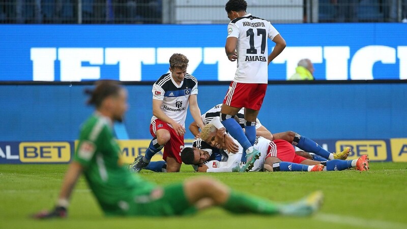 Des einen Freud ist des anderen Leid: Während Jahn-Keeper Thorsten Kirschbaum enttäuscht am Boden des Hamburger Volksparkstadions sitzt, jubeln die Spieler des HSV über den Treffer zum entscheidenden 3:1.