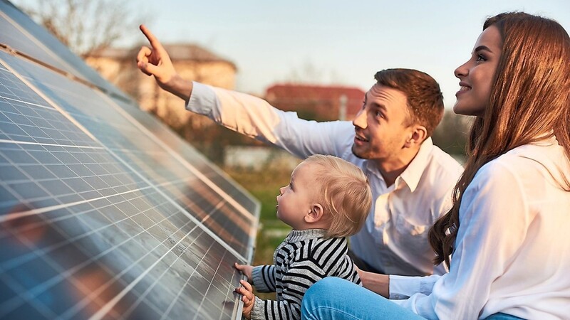 Ein Mann zeigt seiner Familie eine Photovoltaikanlage.