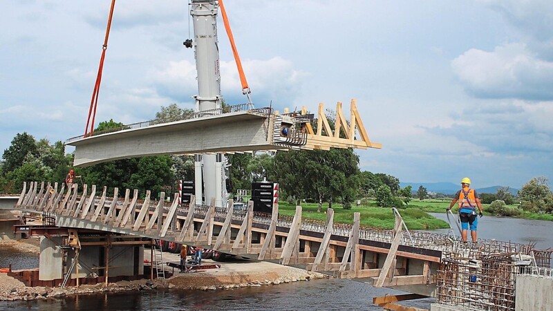 Mittels Kran schweben die 55 Tonnen schweren Stahlbetonträger auf die Brückenpfeiler.