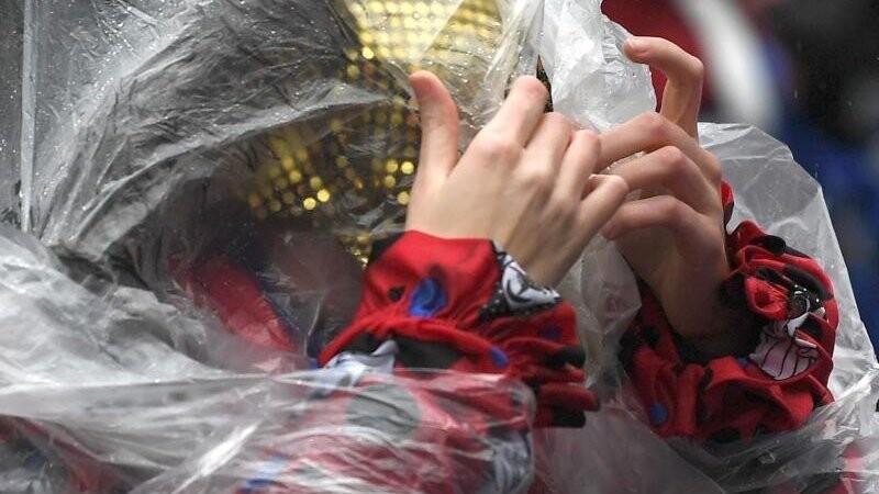Eine Frau schützt sich mit einem Poncho vor dem Regen beim Rosenmontagszug (Archiv). Auch in diesem Jahr wird es wohl nass.