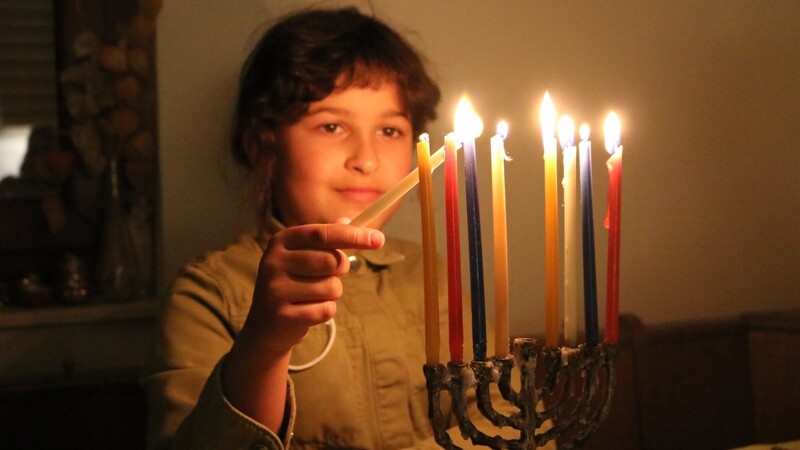 Ayfi (8) zündet mit der Dienerkerze den Chanukkia an: Am achten Tag brennen alle acht Kerzen.