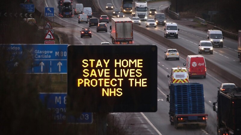 Eine elektronische Anzeige mit der Aufschrift "Stay Home. Save Lives. Protect the NHS" (Bleiben Sie zu Hause. Retten Sie Leben. Schützen Sie NHS, das staatliche Gesundheitssystem) steht neben einer Autobahn. Künftig gilt in Corona-Hotspos ein Bewegungsradius von 15 Kilometern.