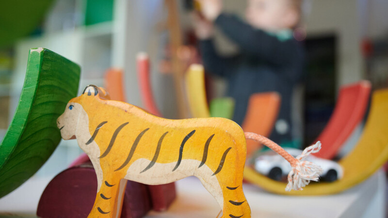 Ein Junge spielt in einem Kindergarten mit Bauklötzen und einem Spielzeugauto.