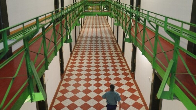 Ein Gefangener geht in der Justizvollzugsanstalt Straubing den Flur vor den Zellen entlang.