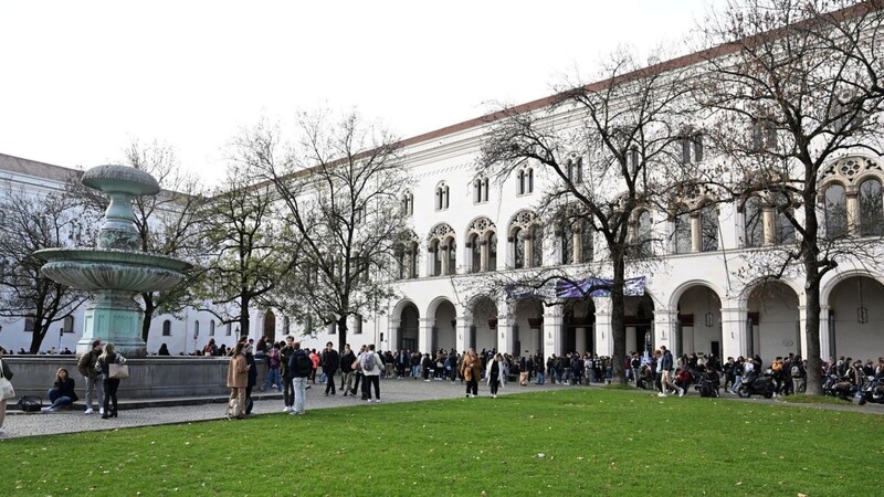 Studenten stehen vor dem Hauptgebäude der LMU.