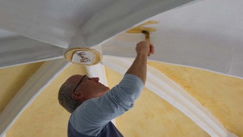 Kirchenmaler Manfred Koller trägt an der Decke der Herrnfeldener Kirche St. Nikolaus einen Lasuranstrich auf.
