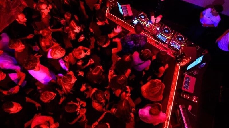 Menschen tanzen in einem Club zu elektronischer Musik.
