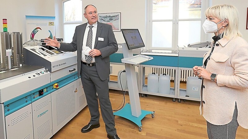 Herbert Wimmer vom ZBFS in Landshut demonstriert Staatsministerin Carolina Trautner die Funktionsweise des "Ausweisdruckers mit Kuvertierung" der Firma Mühlbauer.