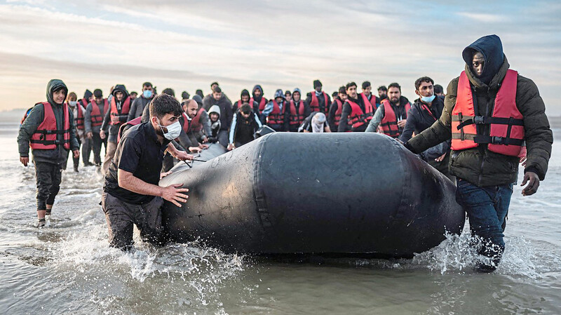 Migranten ziehen ein Schlauchboot aus dem Wasser am Strand von Gravelines. Mehr als 41.000 Menschen sind in diesem Jahr bereits unerlaubt über den Ärmelkanal nach Großbritannien gelangt.