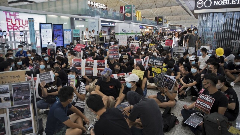 Demonstranten versammeln sich mit Plakaten erneut zu einem Sitzstreik im Terminal des Flughafens Hongkong, um gegen die Polizeigewalt zu protestieren. Es ist zu befürchten, dass der Showdown in Hongkong näher rückt. Die Zeichen stehen auf Gewalt.