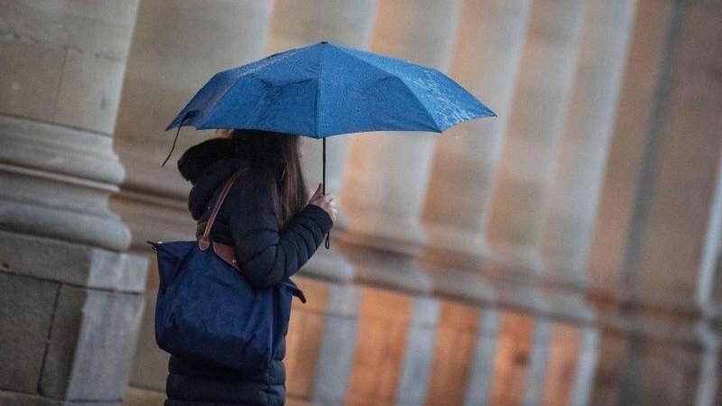 Eine Passantin geht bei Regen durch die Stadt. Foto: Marijan Murat/dpa/Symbolbild
