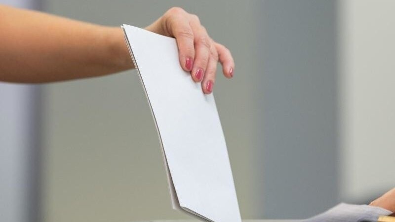 Ein Wahlzettel wird in eine Wahlurne geworfen. Foto: Robert Michael/dpa-Zentralbild/dpa/Symbolbild