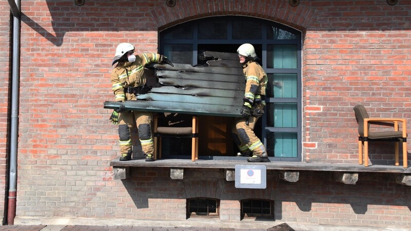 Brand in der Veldener Güterhalle: Feuerwehrleute bringen durch den Brand beschädigte Holzteile aus dem Gebäude.