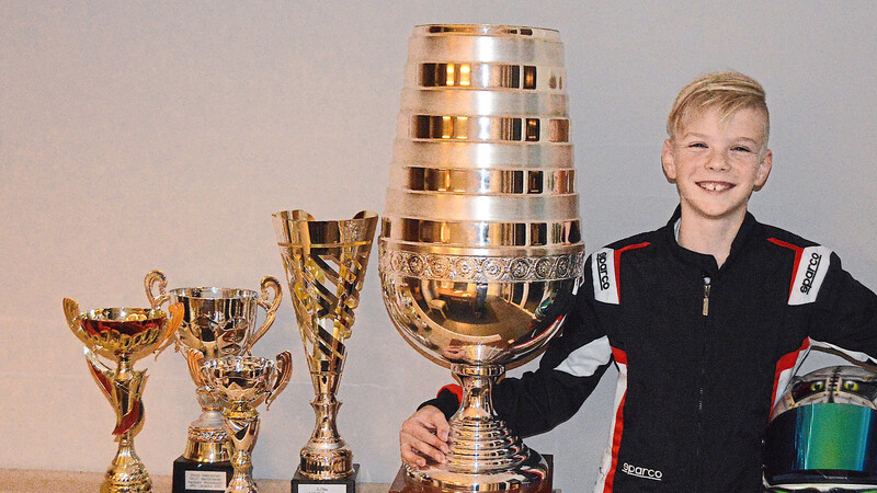 Maxi Flegel präsentiert stolz seine Pokale, darunter der große Sebastian-Vettel-Pokal.
