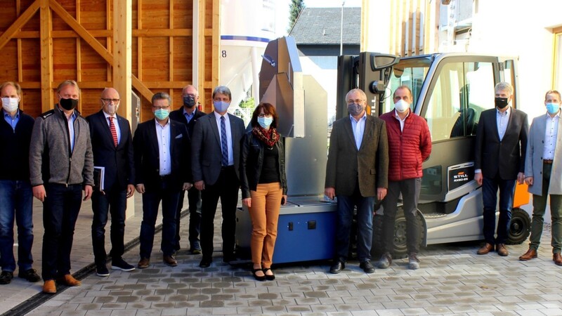 Lehrkräfte, Firmenvertreter, die Vorstandschaft der Bau-Innung Cham und Bürgermeister Bauer vor der neuen Ziegelnassschneidemaschine und dem Stapler.