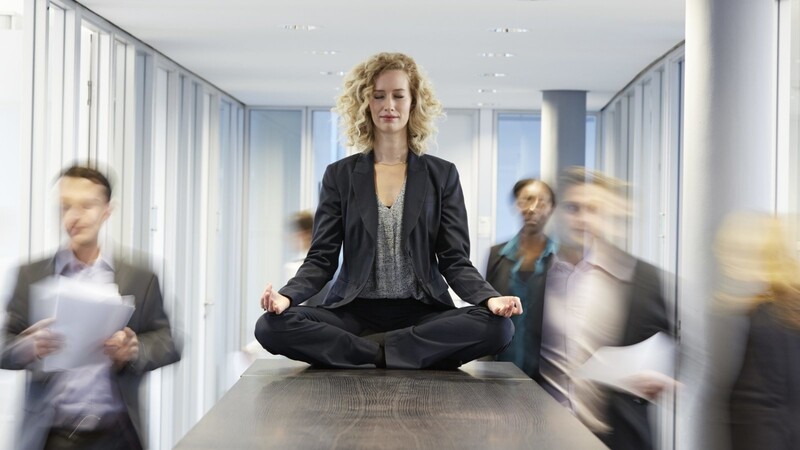 Eine Frau meditiert im Büro. Achtsamkeit kann in Stress-Situationen helfen. (Symbolbild)