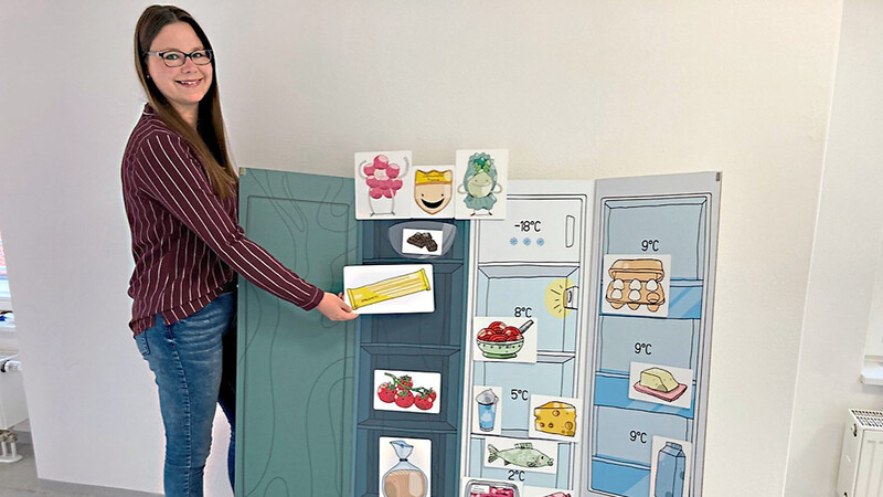 Fachlehreranwärterin Helene Priller zeigt, wie der Vorratsschrank sowie der Kühlschrank fachgerecht eingeräumt werden. "Hmmbeere", "Prinz Köstlich" und "Supersalat" helfen dabei.