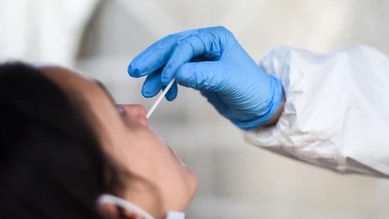 Eine Mitarbeiterin eines Testzentrums entnimmt einer Frau einen Nasenabstrich für einen Corona-Test.