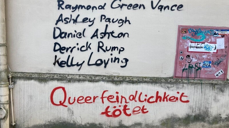 Namen und die Aufschrift "Queerfeindlichkeit tötet" sind an eine Wand gesprüht.