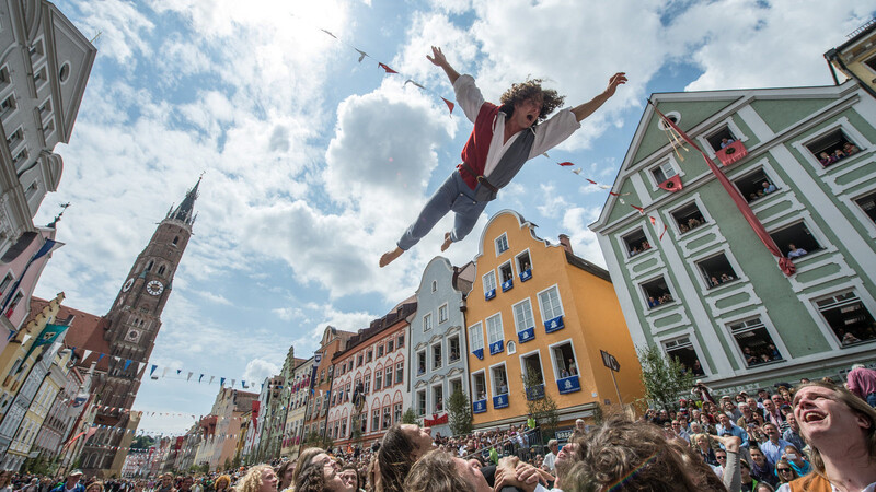 Ein Mann in historischer Kleidung wird in der Altstadt kurz vor dem Umzug der Landshuter Hochzeit in die Luft geworfen.