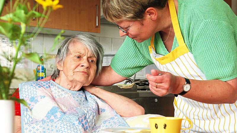 Eine Frau gibt einer pflegebedürftigen Seniorin Brei zu essen. Alte Menschen sind nach einem Krankenhausaufenthalt oft kurz- oder langfristig auf Hilfe angewiesen.