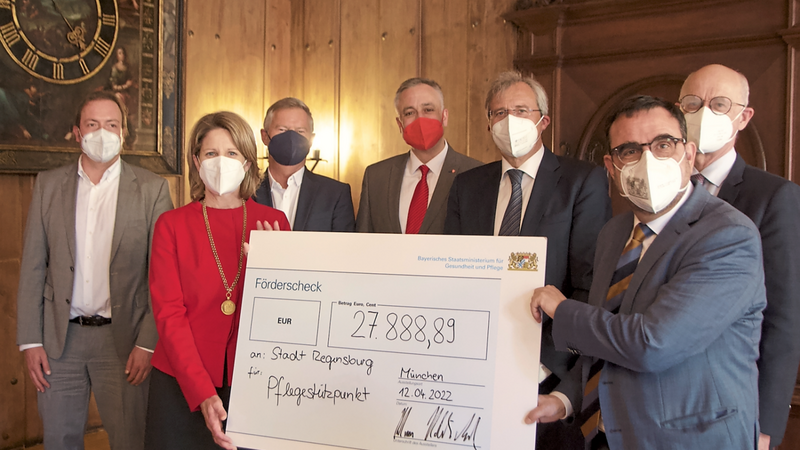 Bayerns Gesundheitsminister Klaus Holetschek (vorne, rechts) bei der Scheckübergabe an Regensburgs Bürgermeisterin Astrid Freudenstein.