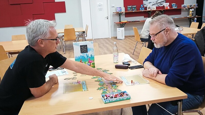 Spiele-Erklärer, Steffen Wallraff, (links) erklärt Besucher Kai Olilver Brand aus Frankfurt beim Seniorennachmittag das Spiel "New York Zoo".