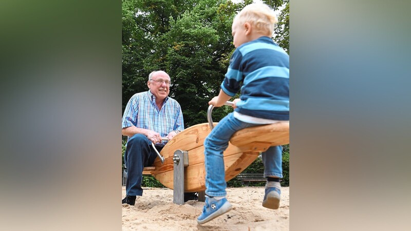 Rauf und runter: Ein Großvater wippt mit seinem Enkel auf einem Spielplatz. Zum ersten Mal findet am Sonntag der Großeltern-Tag in Bayern statt.