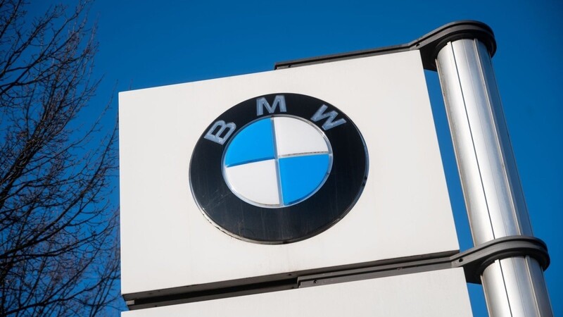 Das Logo von BMW vor einem Werk des Automobilherstellers.