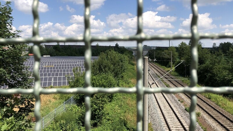 Blick durch die Gitter einer Überführung: Am Horizont verläuft die A92. Sie kreuzt die Bahnstrecke Richtung Mirskofen - laut Gesetz eine privilegierte Stelle für Freiflächen-Photovoltaikanlagen (links im Bild).